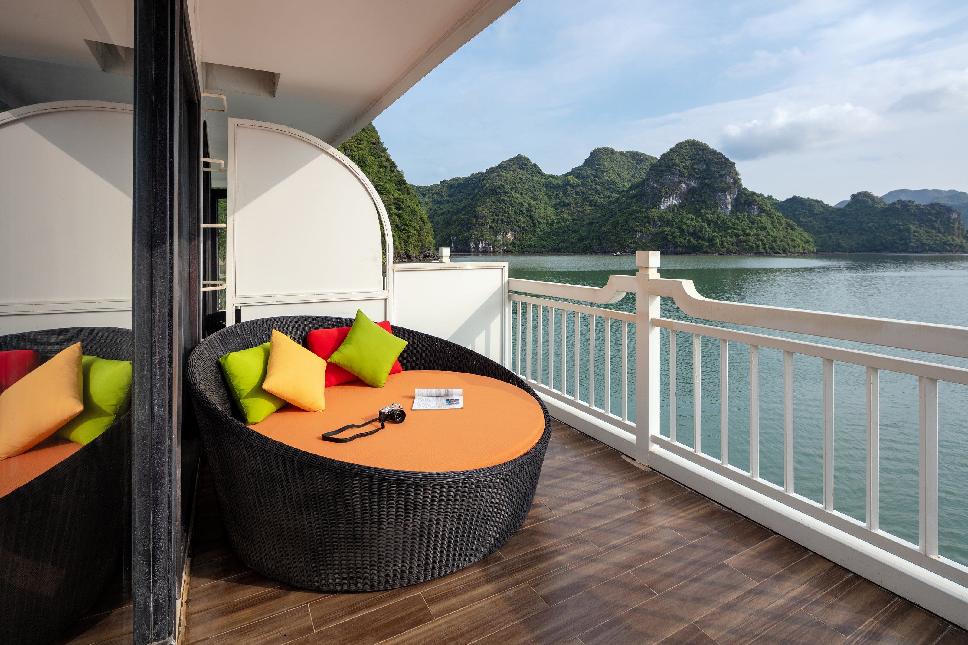 A balcony with wicker furniture and a view of a lake and mountains.