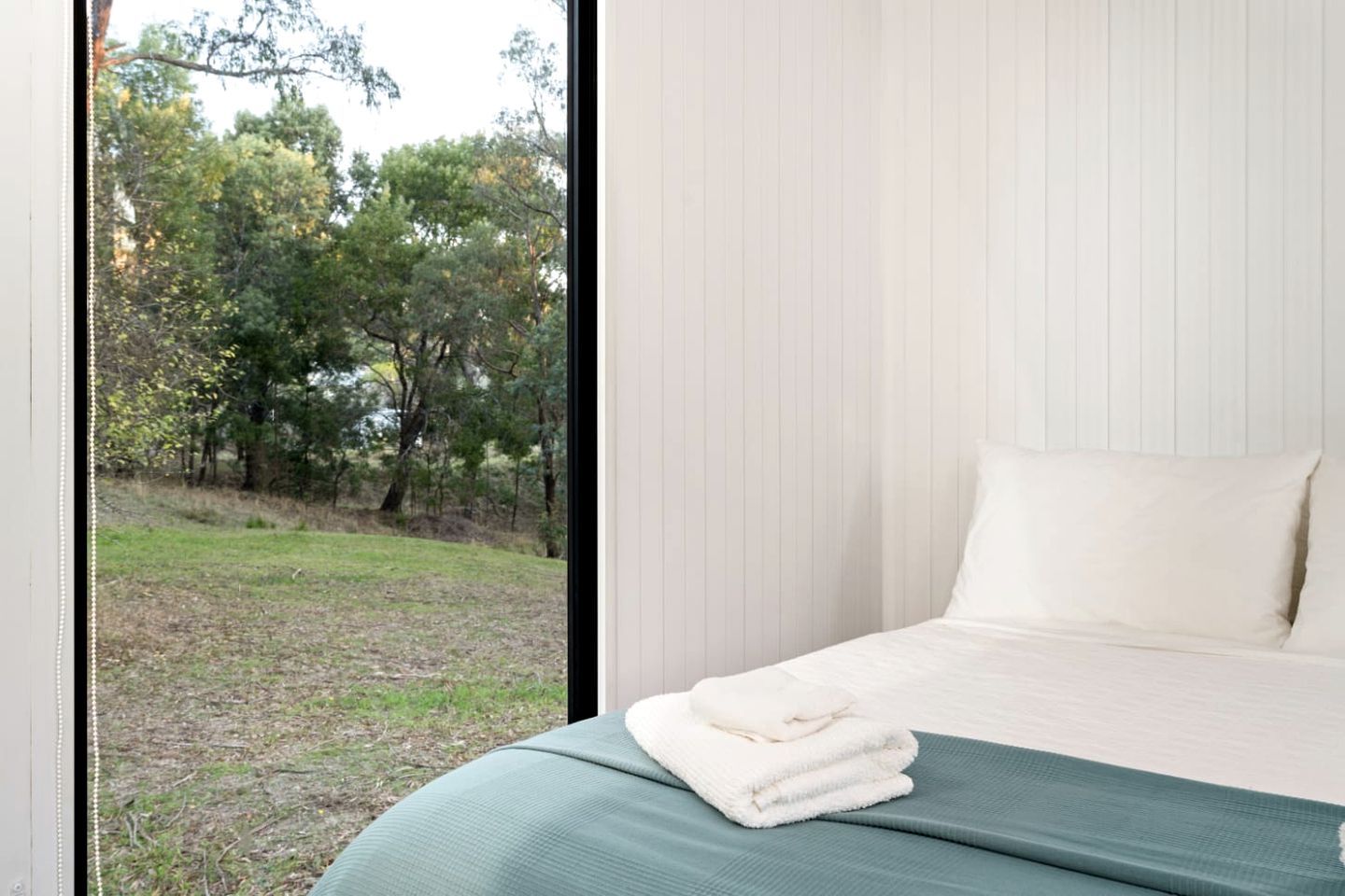 A bedroom with a bed, a window, and a view of trees.