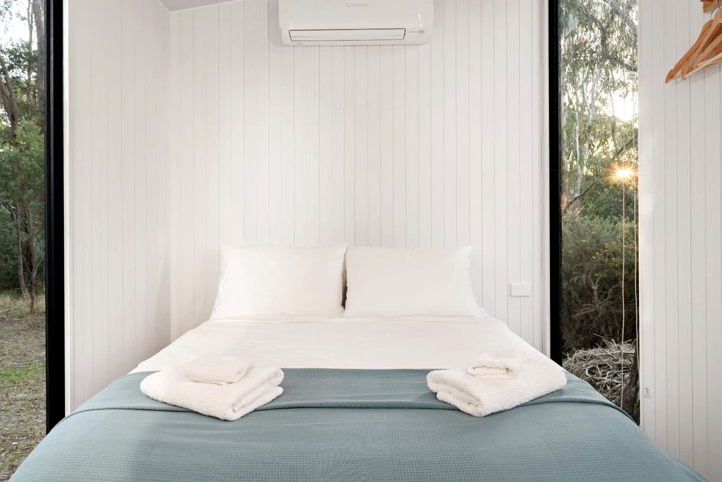 Ein modernes Schlafzimmer mit einem Bett, Kissen und Blick ins Freie.