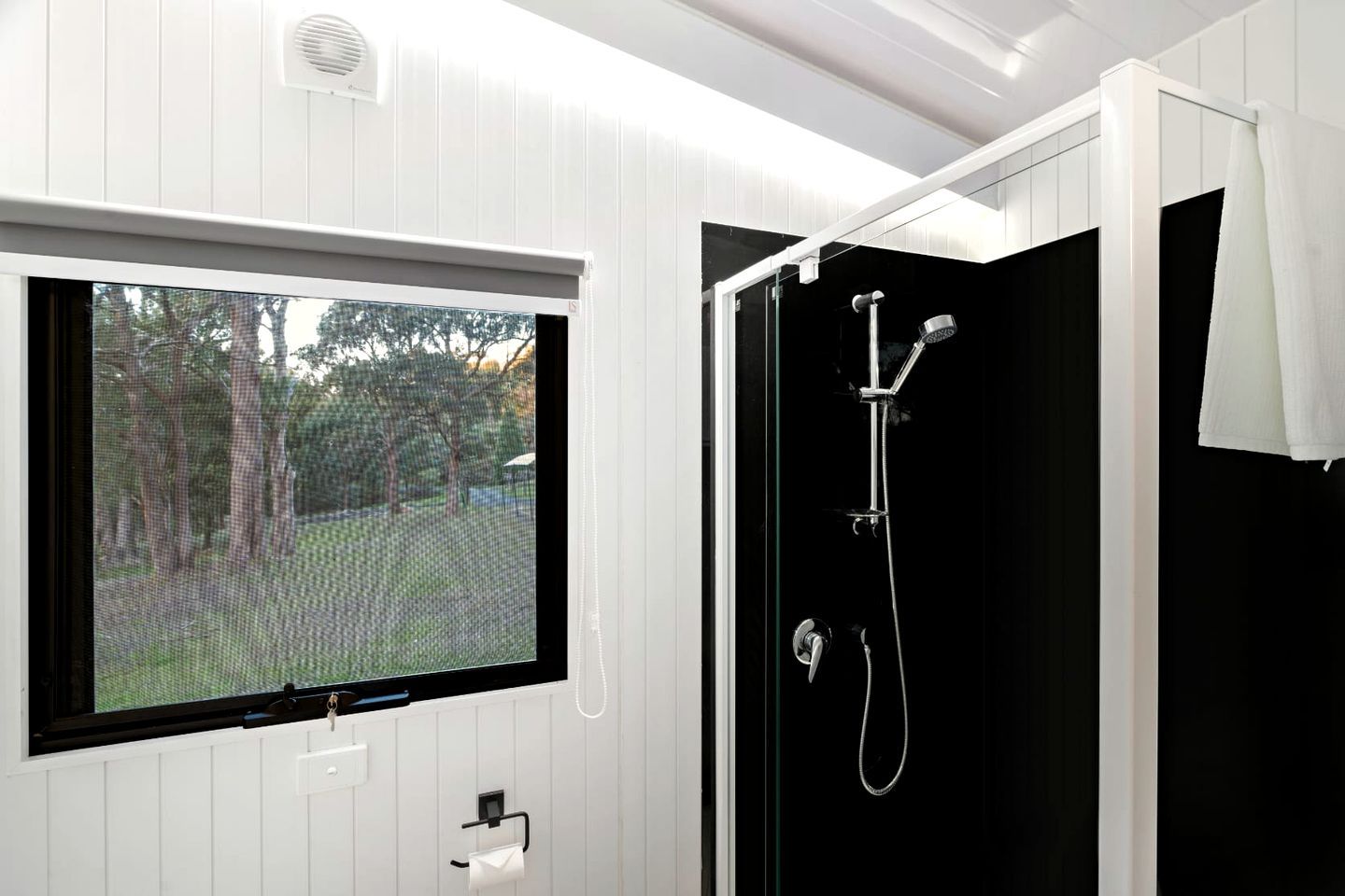 Ein Badezimmer mit Fenster, Dusche und Handtuchhalter.