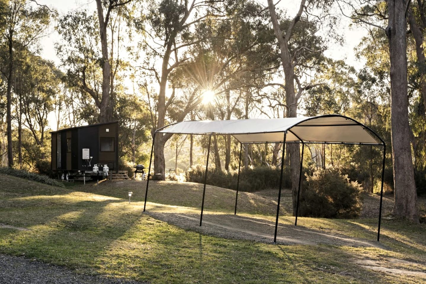 Un espace de camping équipé d’une table de pique-nique couverte et d’une petite cabane.