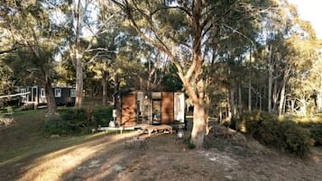 A cabin with a deck, surrounded by trees.