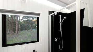 Un baño con ventana, ducha y barra para toallas.