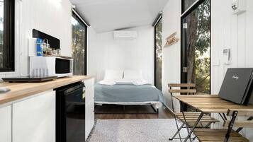 A compact bedroom with a bed, a small desk, and a window.