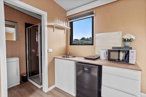A compact kitchen with a sink, a microwave, and a dishwasher. - Cozy Intimate Tiny House Nestled Among Vineyards in South Australia (McLaren Vale)