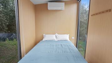 Une chambre avec un lit simple, une fenêtre et un appareil de climatisation.