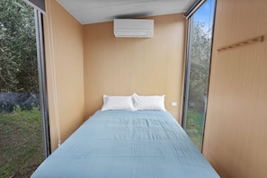 A bedroom with a single bed, a window, and an air conditioning unit.