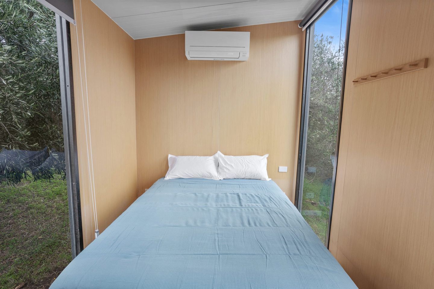 Un dormitorio con una cama individual, una ventana y un equipo de aire acondicionado.