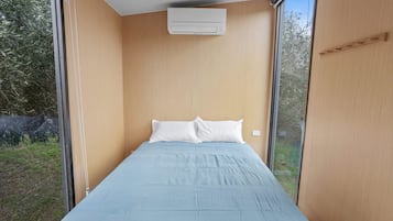 Un dormitorio con una cama individual, una ventana y un equipo de aire acondicionado.