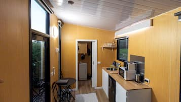 A compact kitchen with a dining area, a small refrigerator, and a microwave.