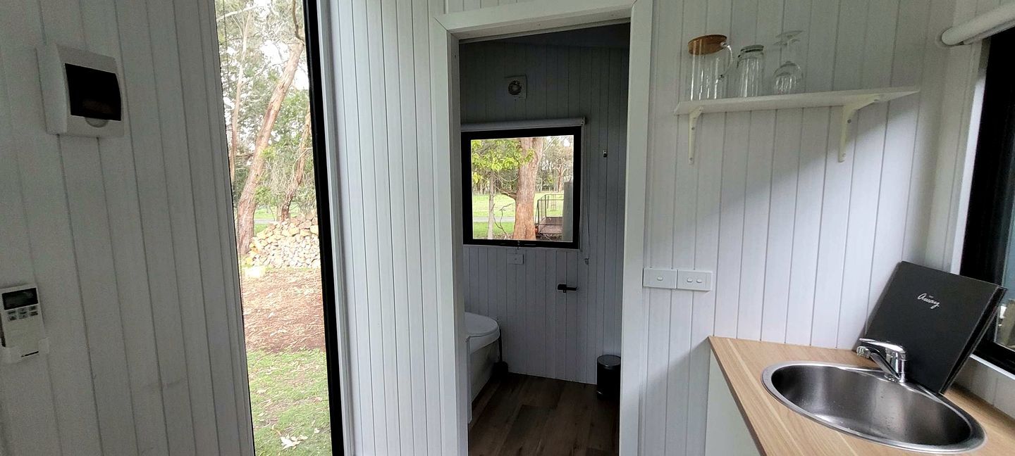 A compact bathroom with a window, a sink, and a small storage shelf.