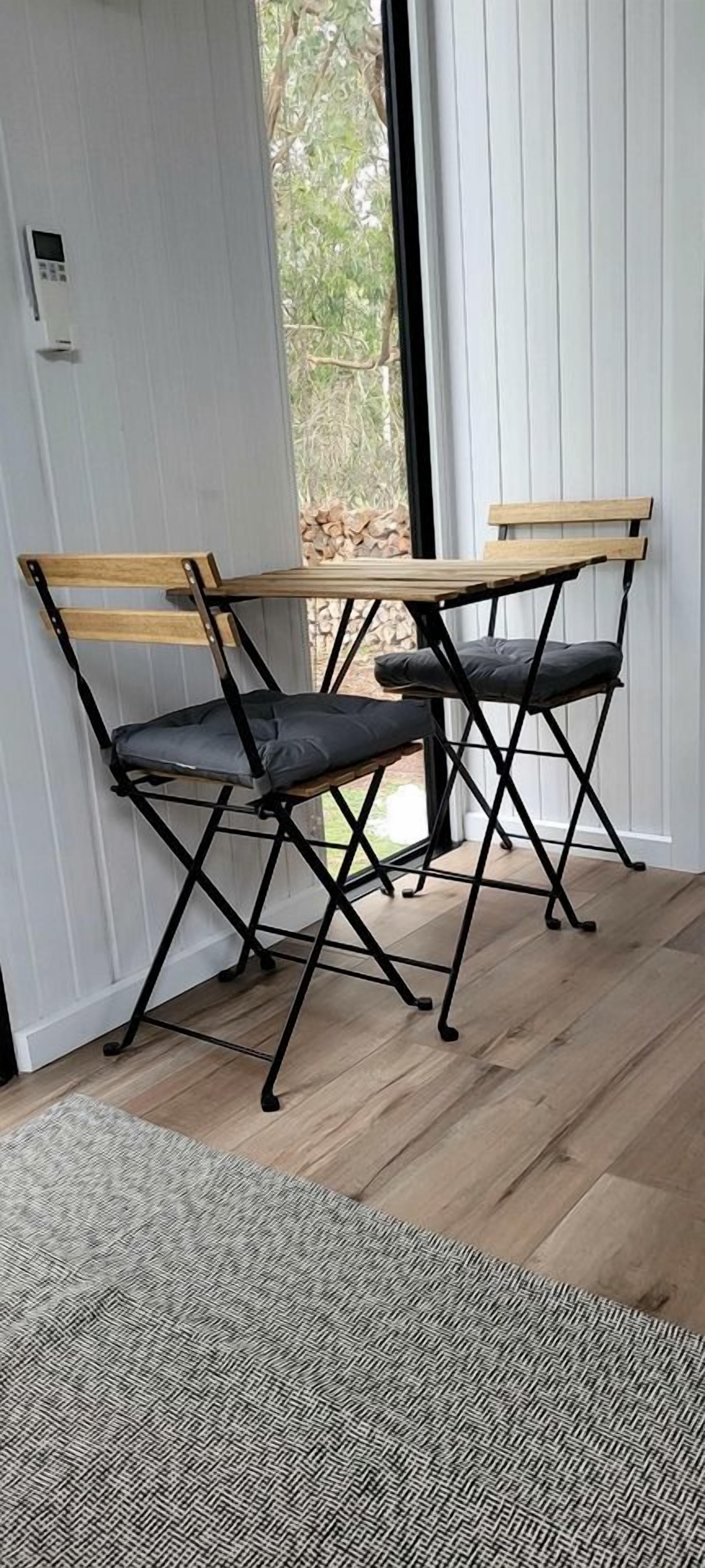 A room with a wooden bench and a black metal frame, a patterned rug, and a door leading to an outdoor area.