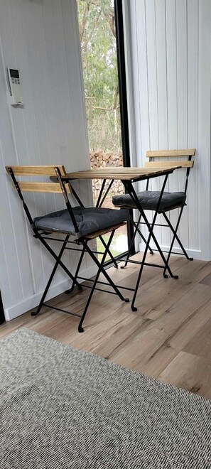 A room with a wooden bench and a black metal frame, a patterned rug, and a door leading to an outdoor area.