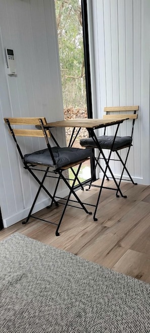 A room with a wooden bench and a black metal frame, a patterned rug, and a door leading to an outdoor area.