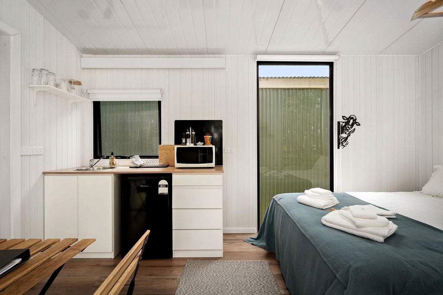 Ein modernes Schlafzimmer mit einem Bett, einem Nachttisch und einer kleinen Küchenzeile.