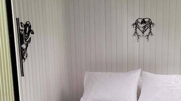 A bedroom with a bed, white walls, and a wooden floor.