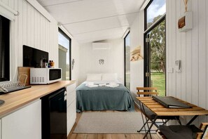 A compact room with a bed, a small kitchenette, and a dining area.