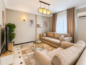 Una sala de estar con sofá, mesa de centro, televisor y planta.