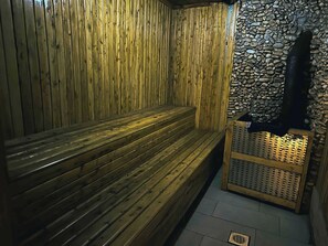 Sauna, jossa on puiset lauteet ja kiviseinä.