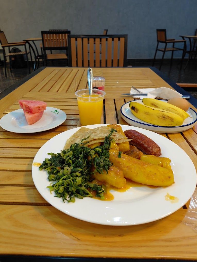 Una mesa de madera con un plato de comida, un vaso de jugo de naranja y un plátano sobre un mantel.