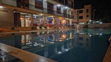 Ein Swimmingpool mit Liegestühlen und einer Bar mit Außenbereich.