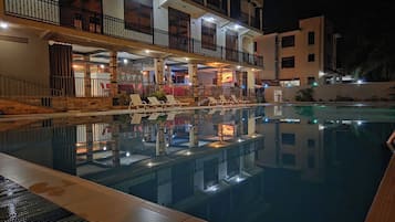 Une piscine avec des chaises longues et un espace bar doté de sièges en plein air.