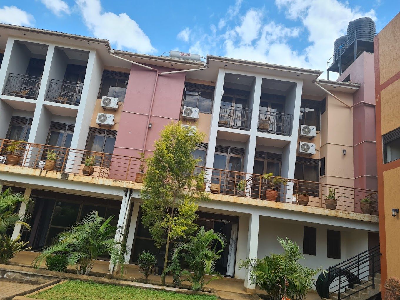 A multi-story building with balconies, air conditioning units, and potted plants.