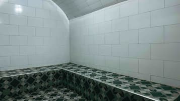 A bathroom with white tiled walls, a green and white patterned floor, and a curved ceiling.