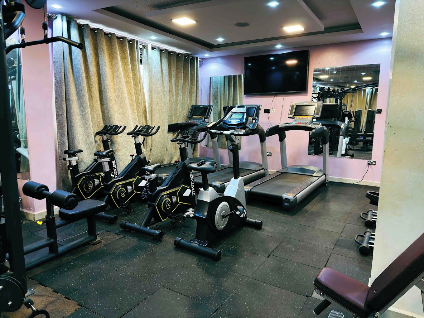 Une salle de sport équipée de tapis de course, de vélos d’appartement et d’appareils de musculation.