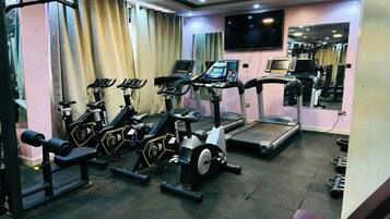 Une salle de sport équipée de tapis de course, de vélos d’appartement et d’appareils de musculation.
