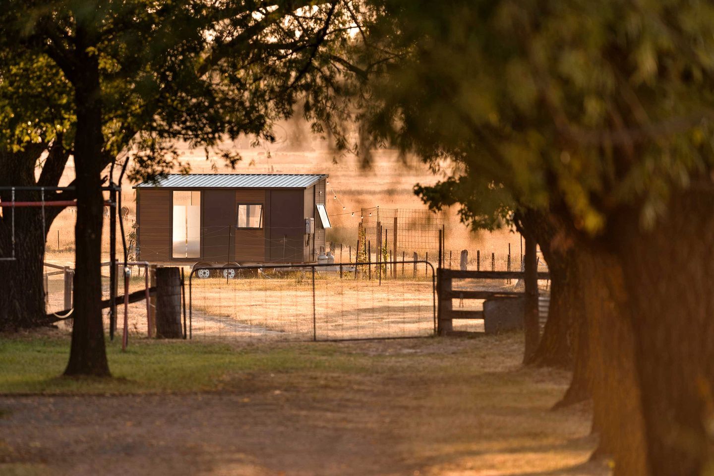 A fenced area with a small building, trees, and a bench.