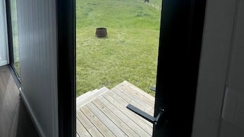 Uitzicht vanuit een kamer met een deur die uitkomt op een houten terras.