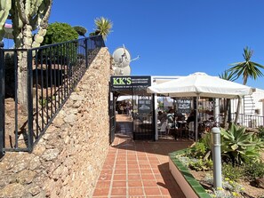 Ein Restaurant mit Terrassensitzgelegenheiten, einer Steinmauer und wolkenlosem, blauem Himmel.