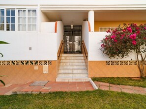 Ein Gebäude mit einer Treppe zu einer Tür, einem kleinen Garten mit Rasen und einer Wand mit dekorativem Muster.