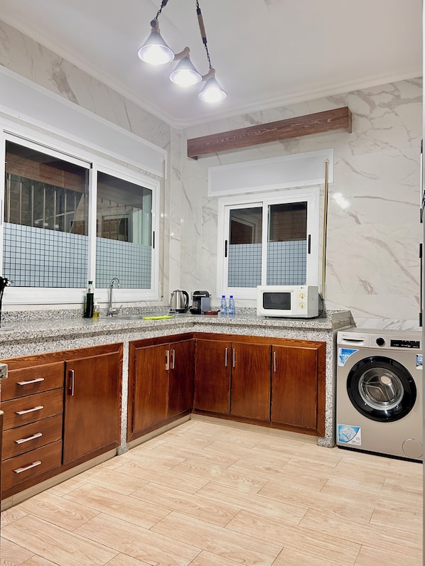 Una cocina con armarios de madera, microondas integrado y lavadora.