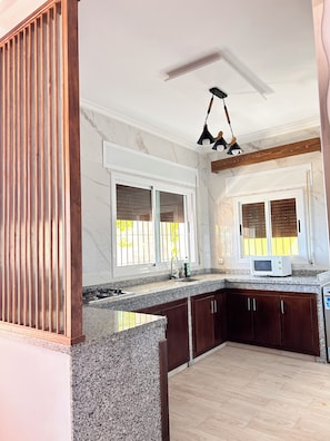 A kitchen with granite countertops, wooden cabinets, and a built-in microwave.