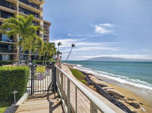 A beachfront hotel with a gated entrance, palm trees, and a view of the ocean. - New Luxury Retreat  Vast Ocean Views & Huge Lanai (Lahaina)