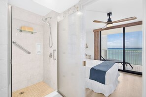 A hotel room with a shower, a balcony with a view of the sea, and a bed with a blue bedspread. - New Luxury Retreat  Vast Ocean Views & Huge Lanai (Lahaina)