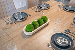 A dining table set with plates, cutlery, and glasses, with a decorative centerpiece of green spheres. - Beachfront Nirvana | Corner View • Pool • Gym (Hollywood)