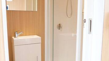 A bathroom with a glass-enclosed shower, a white sink, and a wooden vanity.