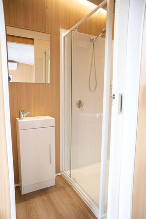 A bathroom with a glass-enclosed shower, a white sink, and a wooden vanity. - Relaxing Tiny House Escape with Stunning Rocky Creek Views, Nestled in the Foothills of the Bauple Mountains in Glenwood, New South Wales (Glenwood)