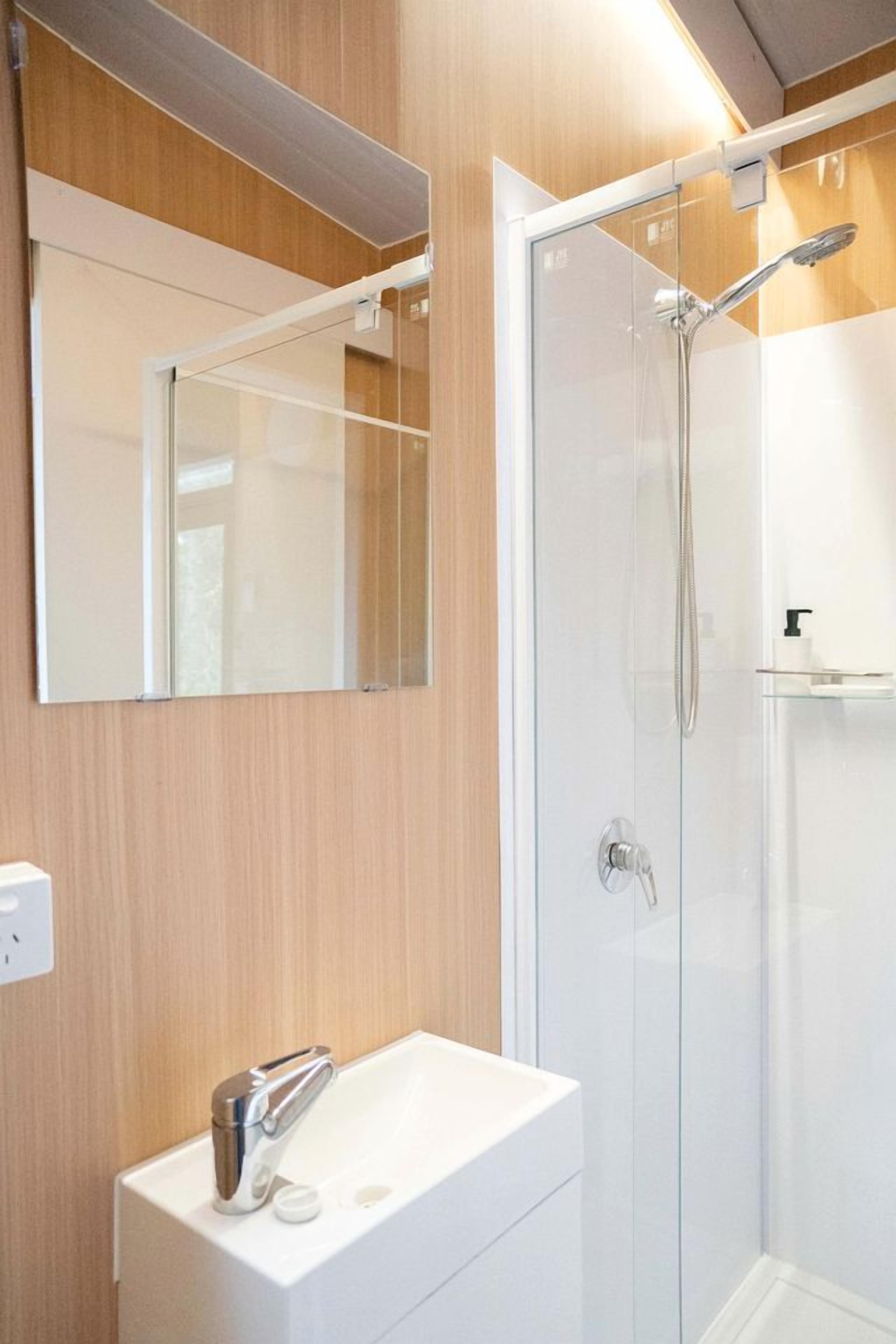 Een moderne badkamer met een douchecabine van glas, een wit wastafelmeubel en een spiegel.
