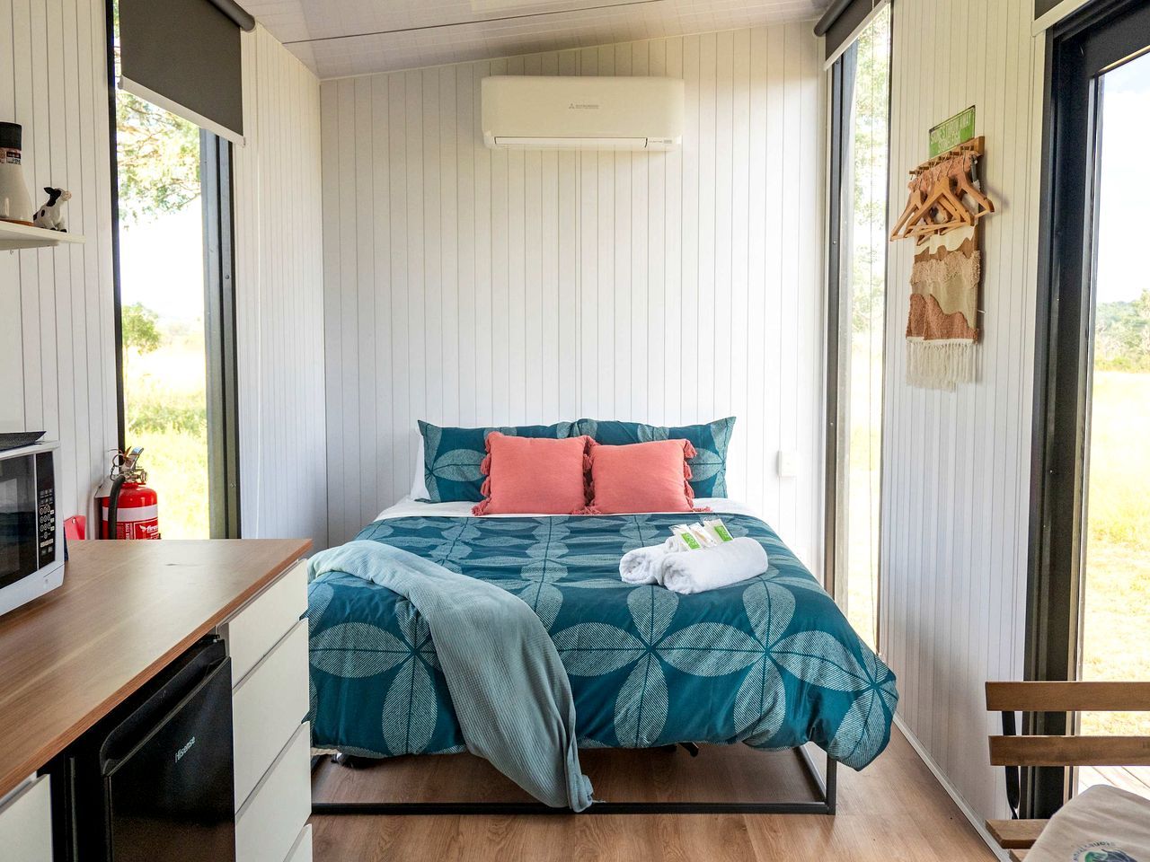 Une chambre avec un lit, une table de chevet, un four à micro-ondes, un extincteur et une fenêtre.