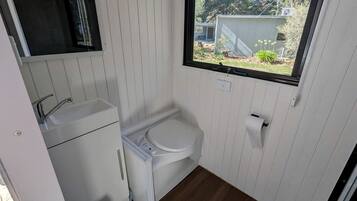 Une petite salle de bain comprenant des toilettes, un lavabo et une fenêtre.