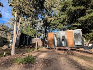 Varias casas móviles modernas con paredes exteriores, algunas con puertas correderas, y una mesa de picnic al frente.