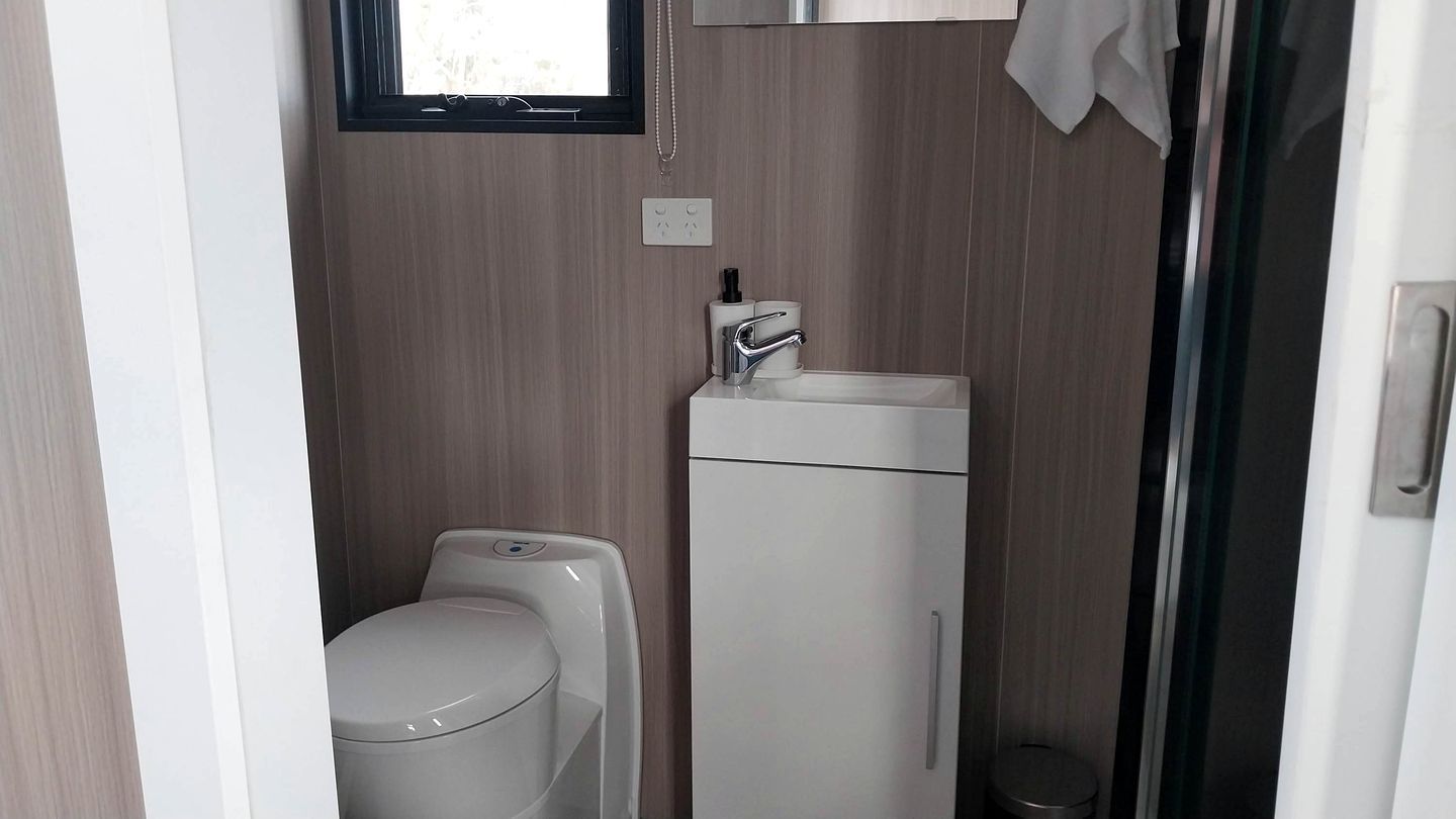 Un baño pequeño con inodoro, lavabo y un pequeño cubo de basura.