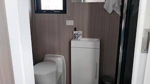 A compact bathroom with a toilet, sink, and a small trash bin.