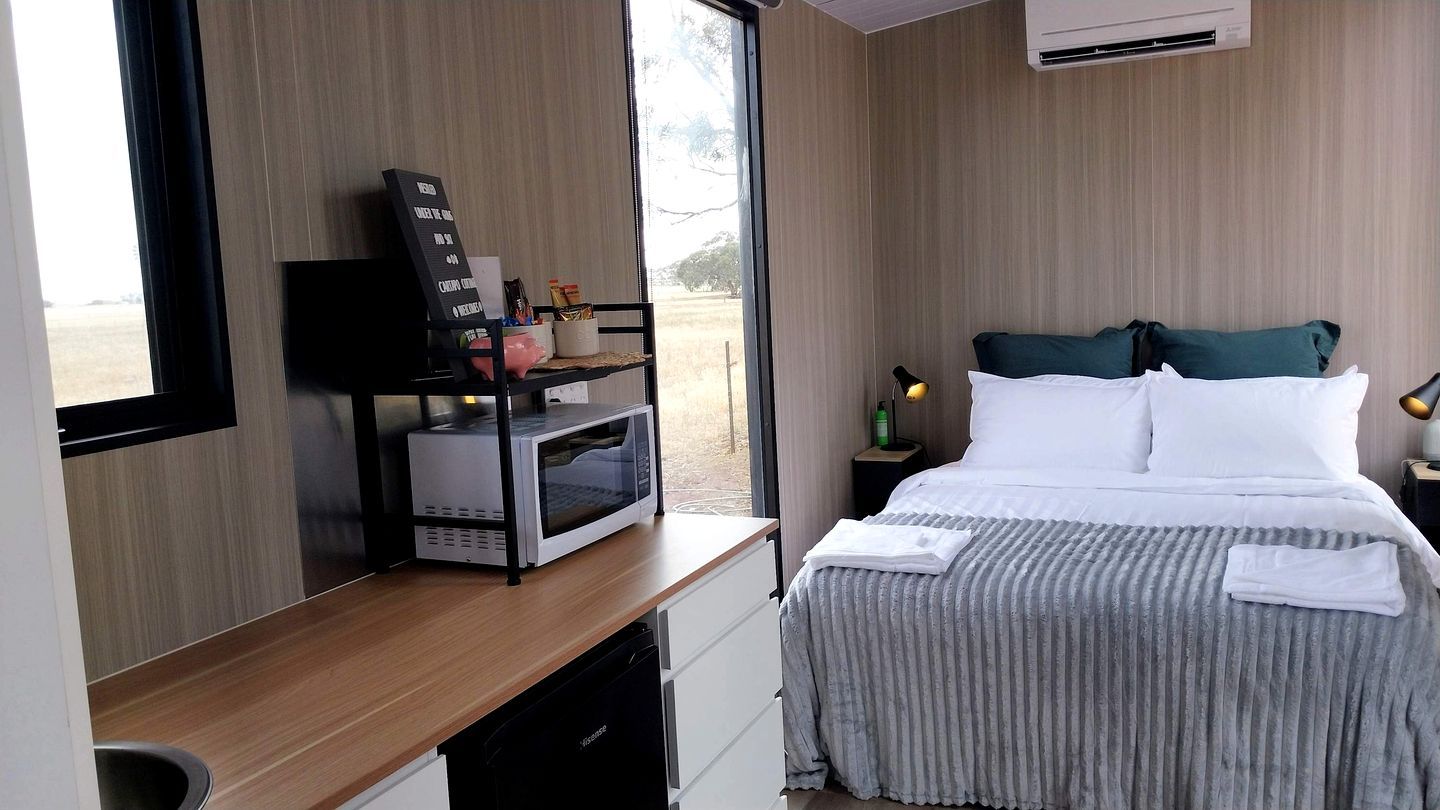 Una camera d'albergo con un letto, un comodino, un forno a microonde e vista sull'esterno.