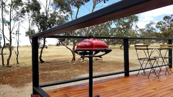 A wooden deck with a barbecue grill and folding chairs.