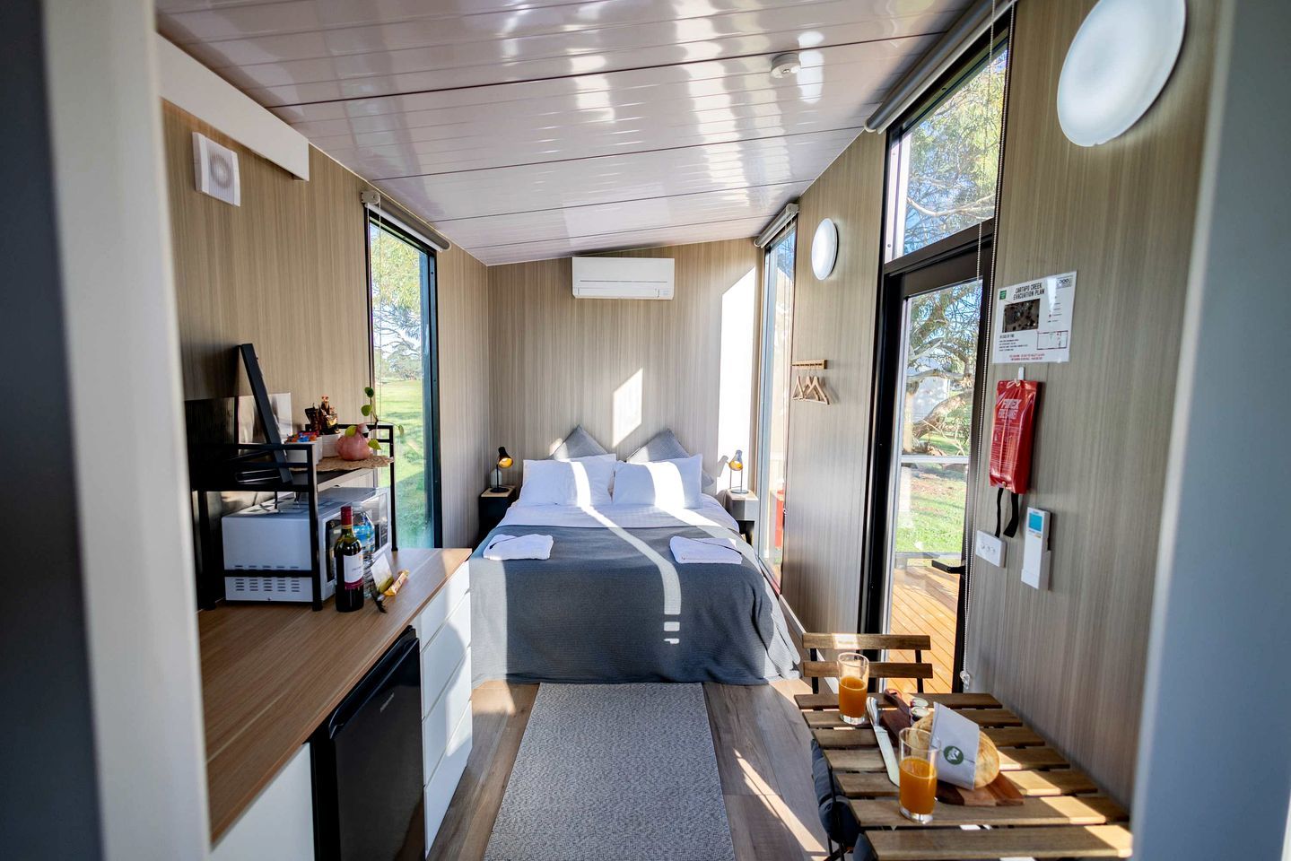 Una habitación moderna y funcional con cama, mesita de noche y vistas al exterior.